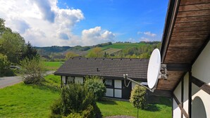 A house with a satellite dish, surrounded by green fields and hills. - Holiday Home in Mielinghausen Near ski Area (Meschede)