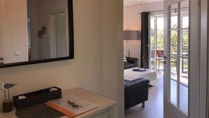 A modern hotel room with a large mirror, a small desk with a basket, and a view of the outdoor balcony area. - Familienfreundliches Ferienhaus (Oldenburg in Holstein)