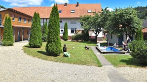 A courtyard with a swimming pool, surrounded by buildings with red-tiled roofs and neatly trimmed trees.