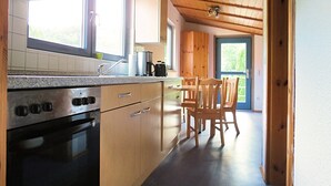 A kitchen with wooden cabinets, a stainless steel stove, and a window overlooking a balcony.