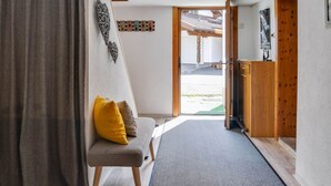 Una habitación con una cama, un banco con cojines, un armario de madera y una puerta que da al exterior.