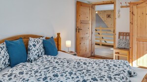 Un dormitorio con una cama de madera, una mesita de noche, una lámpara y una silla de madera.