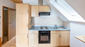 A kitchen with wooden cabinets, a built-in oven, a stove, and a skylight. - Chalet in Frankenau Nahe Skipisten & Edersee (Frankenau)