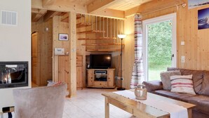 Un intérieur en bois avec une cheminée, un téléviseur, un canapé et une table à manger.