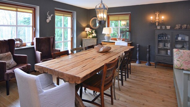 A dining area with a wooden table and chairs, a chandelier, and a cabinet with dishes. - Quaint Holiday Home near Ski Area in Neuastenberg (Winterberg)