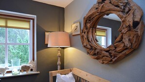 A bedroom with a wooden headboard, a round mirror, a lamp, and a window with a view of greenery. - Quaint Holiday Home near Ski Area in Neuastenberg (Winterberg)