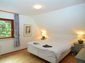 A bedroom with a large bed, two bedside tables with lamps, a window with curtains, and a painting on the wall. - Quaint Holiday Home near Ski Area in Neuastenberg (Winterberg)