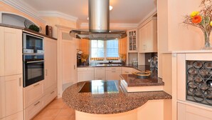 A modern kitchen with built-in appliances, a central island, and a decorative vase. - Apartment in Bavaria With Scenic Garden Views (Deggendorf)