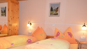 A double bed with floral bedding, wooden headboard, and nightstands with lamps. - Cozy Apartment near Ski Area in Tschagguns (Tschagguns)
