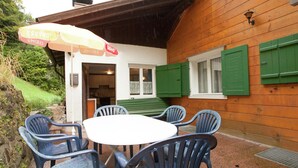 A wooden building with a covered patio area featuring a round table and four chairs. - Cozy Apartment near Ski Area in Tschagguns (Tschagguns)