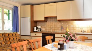 A compact kitchen with a dining area, featuring a sofa, chairs, a table with a placemat, and a refrigerator. - Cozy Apartment near Ski Area in Tschagguns (Tschagguns)