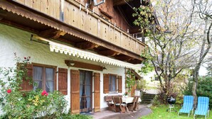 A traditional wooden house with a balcony, a covered porch, and a garden with flowers and a lawn. - Spacious Apartment in Steingaden near Ski Area (Steingaden)