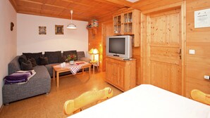A cozy wooden interior with a sofa, a TV on a wooden cabinet, a table with a lamp, and a dining area. - Spacious Apartment in Steingaden near Ski Area (Steingaden)