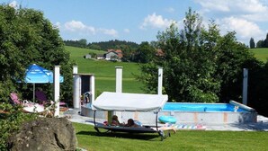 A swimming pool area with a slide, lounge chairs, and a small building with a door. - Spacious Apartment in Steingaden near Ski Area (Steingaden)