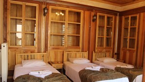 Hotellihuone, jossa on neljä erillistä sänkyä, puukaappeja ja suuri ikkuna.