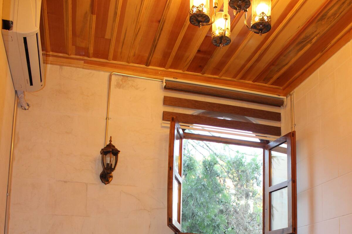 Une pièce avec un lit, une fenêtre, un radiateur et une lampe.