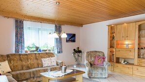Una sala de estar con sofá, sillón, mesa de centro y un aparador de madera.