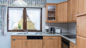 Una cocina con armarios de madera, lavavajillas, cafetera, tostadora y estufa.
