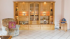 Una sala de estar con un aparador de madera, un sillón mullido y una pequeña mesa de madera.