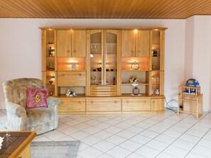 A living room with a wooden cabinet, a cushioned armchair, and a small wooden table.
