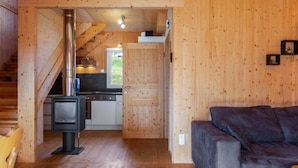 A cozy cabin interior with a wooden interior, a fireplace, a kitchen area, and a sofa. - Luxury Chalet in Hohentauern near Ski Area (Hohentauern)