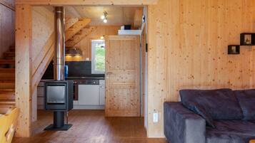 Ein gemütliches Blockhaus-Interieur mit Holzausstattung, Kamin, Küchenbereich und einer Couch.