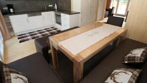 Une cuisine moderne avec des meubles blancs, un plan de travail noir et une table à manger en bois agrémentée d’un set de table.