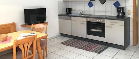 Una cocina compacta con comedor, que incluye un televisor, una cafetera y un tostador.