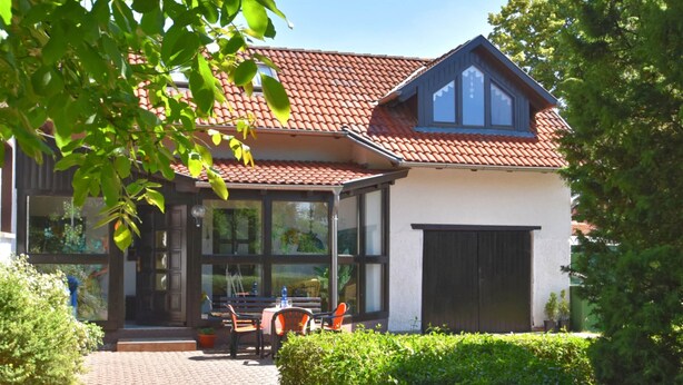 A house with a red-tiled roof, large windows, and a patio with outdoor seating. - Sophisticated Holiday Home With Garden (Grabfeld)
