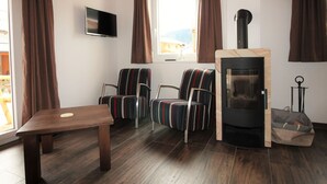 Un accogliente soggiorno con un tavolo in legno, poltrone a righe, un camino e un televisore appeso al muro.