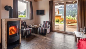 A cozy room with a wood-burning stove, two striped armchairs, a small table, and a TV.