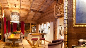 A wooden interior with a dining area, kitchen, and seating. - Fürsten Chalet (Flachau)