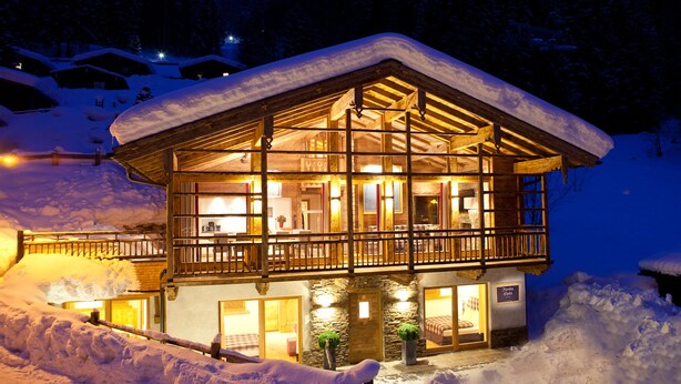 A snow-covered lodge with a wooden exterior and large windows, surrounded by snow. - Fürsten Chalet (Flachau)
