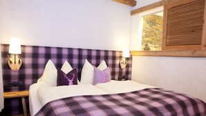 A bedroom with a plaid headboard, two bedside lamps, and a window with wooden shutters. - Fürsten Chalet (Flachau)