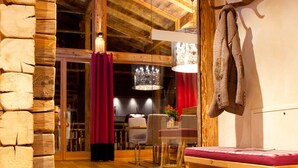A cozy wooden interior with a stone wall, a bench, and a pair of shoes on the floor. - Fürsten Chalet (Flachau)