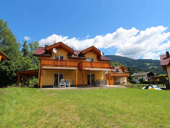 A two-story chalet with a balcony, a covered patio, and a view of the surrounding mountains. - Chalet in Kotschach Near Family Ski Area (Kotschach-Mauthen)