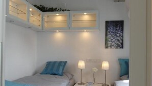 Una camera da letto piccola e luminosa con due letti, un comodino con lampade e un lampadario.