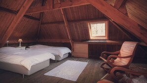 Een knus zolderkamer met twee bedden, een bureau en een stoel.