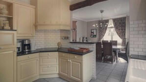 Een keuken met lichte kasten, een zwart aanrechtblad en een eethoek met een tafel en stoelen.