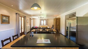 Una cocina moderna con una isla grande, muebles de madera, un refrigerador de acero inoxidable y un comedor con mesa y sillas.