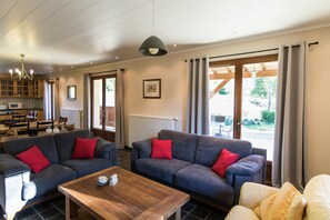 A living room with two sofas, a wooden coffee table, a chandelier, and a view of the outdoors.
