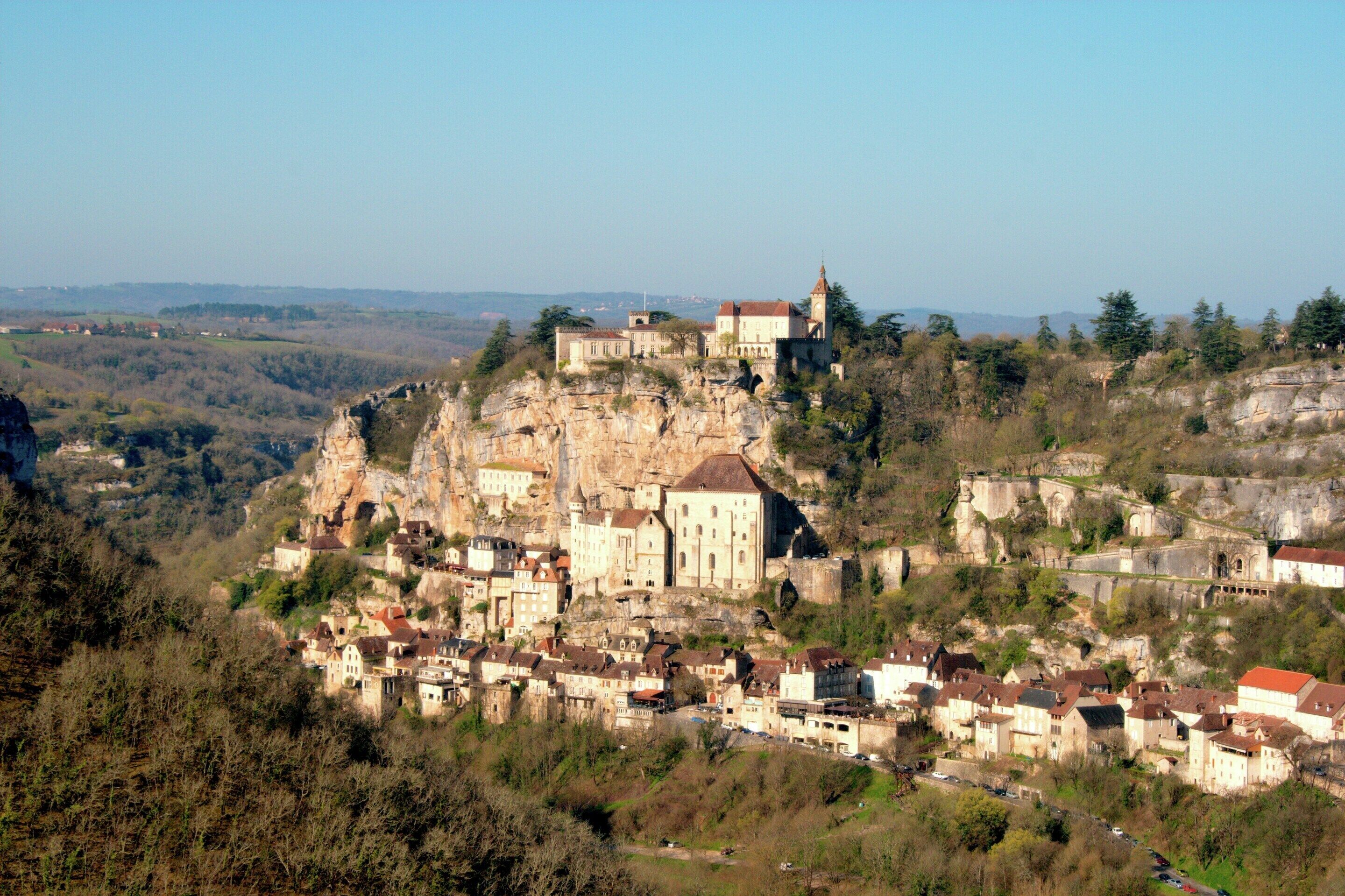 Eine historische Stadt, die auf einem steilen Felsen erbaut wurde, mit einer markanten Kirche und festungsähnlichen Gebäuden.