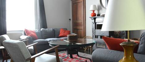 A living room with a sofa, armchairs, a coffee table, and a fireplace.