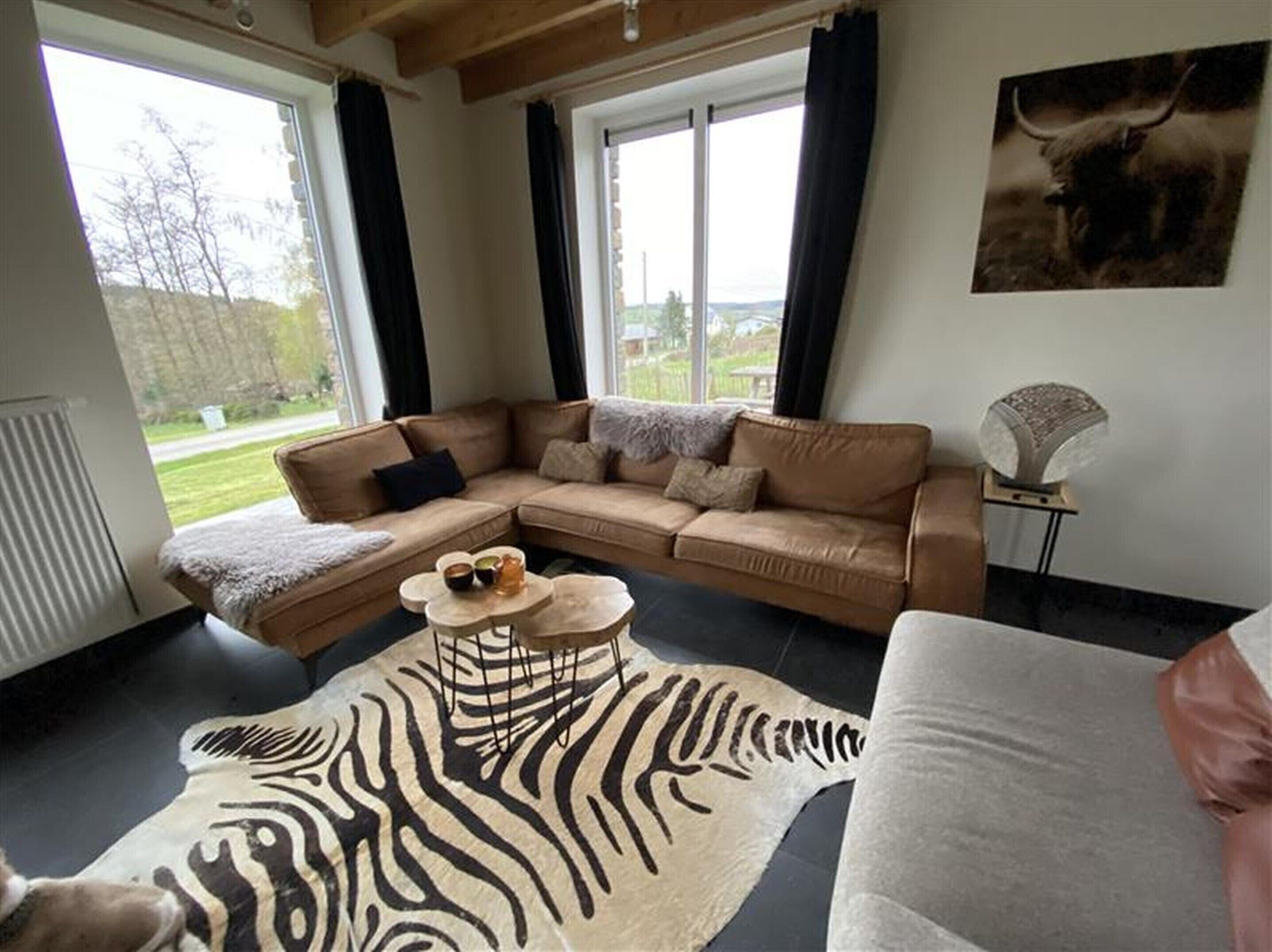 A living room with a L-shaped sofa, a zebra-patterned rug, and a bull-themed artwork on the wall.