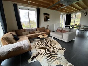 A spacious living room with a large sofa, a smaller sofa, and a coffee table. There is a large window providing natural light and a view of the outdoors. - Cosy Holiday Home in Durbuy With Garden (Durbuy)