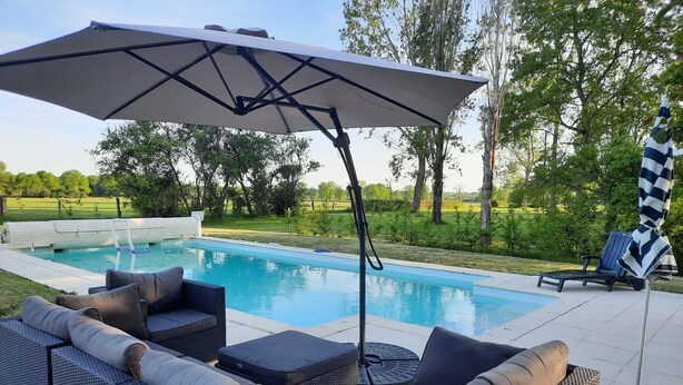 A poolside area with a lounge chair, a sofa, and an umbrella. - Beautiful Authentic Holiday Home With Pool (Chantenay-Saint-Imbert)