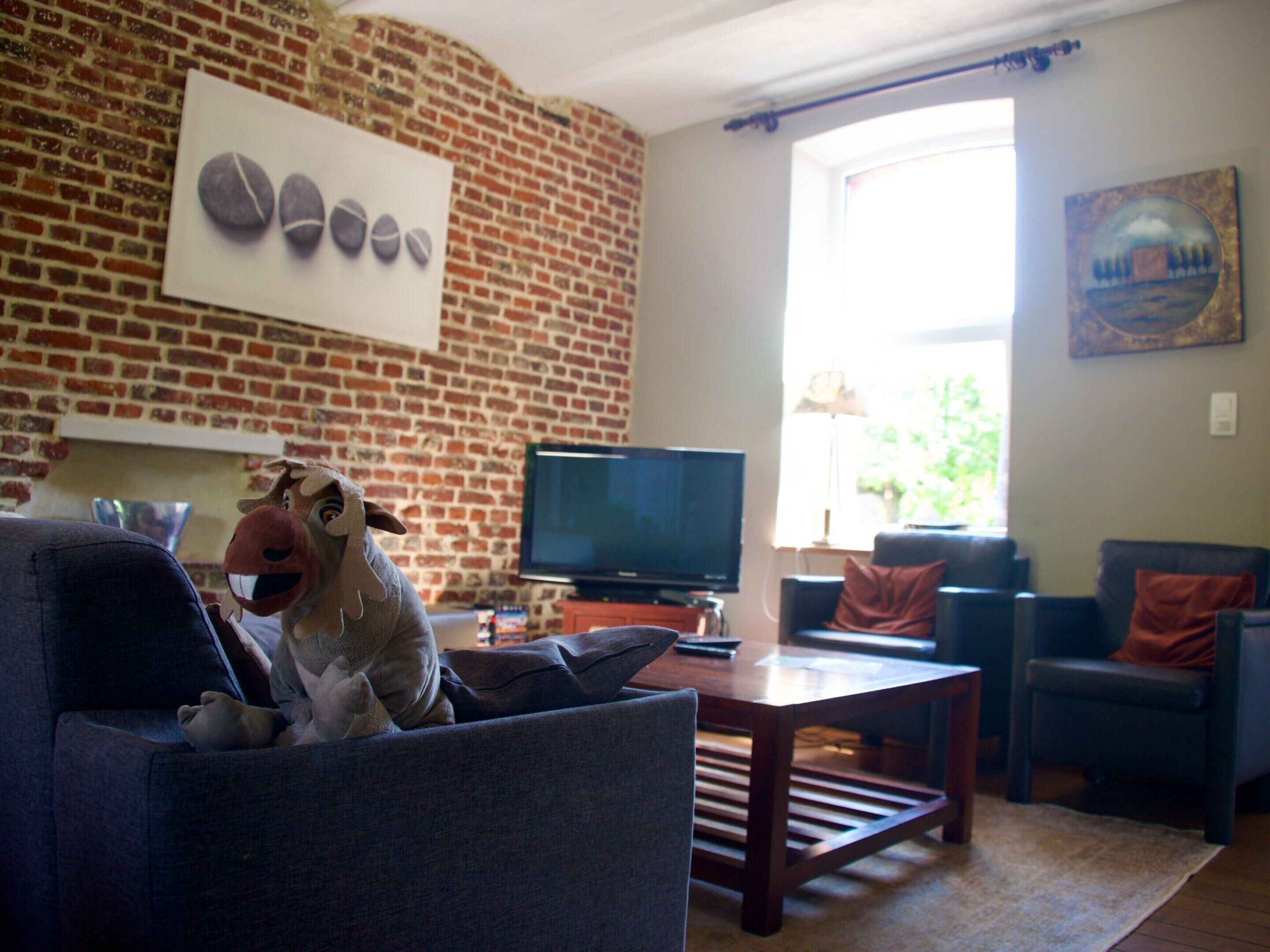 Ein Wohnzimmer mit Backsteinwand, Fernseher und großem Fenster.