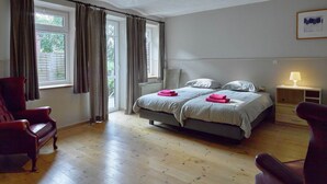 A bedroom with a bed, two bedside tables, a chair, a window with curtains, and a ceiling light fixture. - House in Former Monastery (Sint-Truiden)