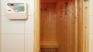 Un sauna en bois avec un panneau de commande sur le mur, sur lequel est inscrit le mot « helo ».