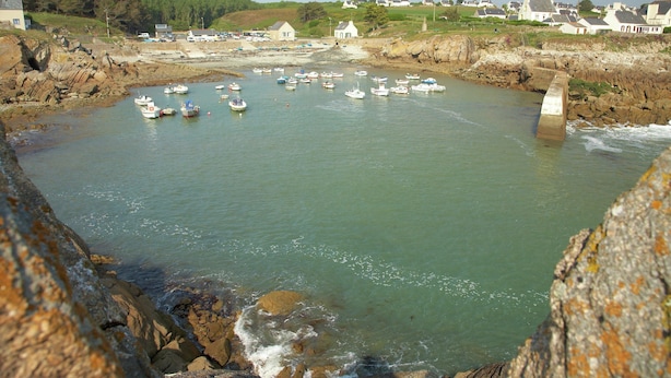 A coastal harbor with boats docked, a rocky shoreline, and houses in the background. - Brittany Escape With Garden (Cleden-Cap-Sizun)